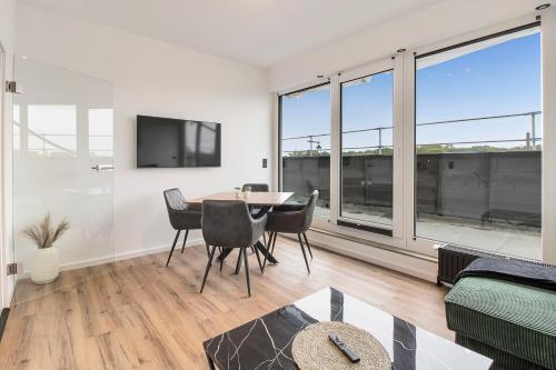 a living room with a table and chairs and windows at 24-7 Living - Lüdinghausen Apartments in Lüdinghausen
