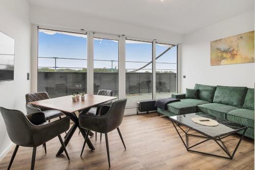 a living room with a table and a green couch at 24-7 Living - Lüdinghausen Apartments in Lüdinghausen