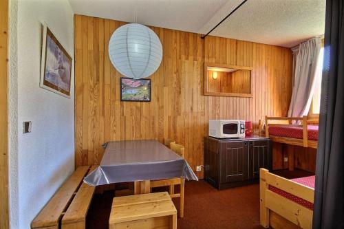 Cette petite chambre comprend une table et un four micro-ondes. dans l'établissement La Plagne Appartement 5 couchages Skis aux pieds, à La Plagne Tarentaise