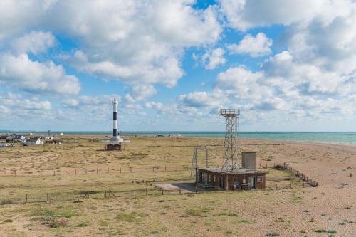 a lighthouse on a beach next to the ocean at Fog Signal Building by Bloom Stays in Littlestone-on-Sea
