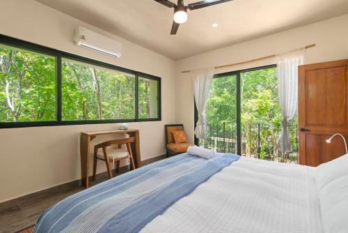 a bedroom with a bed and a desk and windows at 1-BR Gem Apartment Villa Sofia in Chemuyil