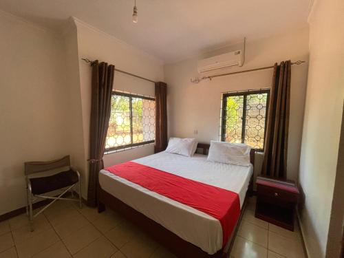 1 dormitorio con 1 cama con manta roja y 2 ventanas en Brian's Hostels, en Moshi