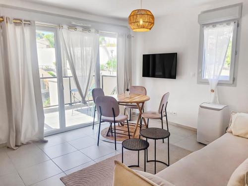 un salon avec une table, des chaises et un canapé dans l'établissement Séjour Central Cavalaire sur Mer - Élégance & Confort, à Cavalaire-sur-Mer