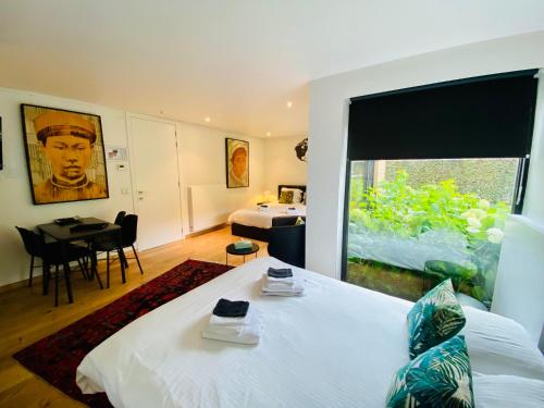 a bedroom with a white bed and a large window at Casa Tilleghem in Bruges
