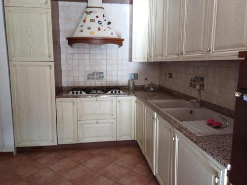 a kitchen with white cabinets and a sink at Max House in Marina di Cerveteri