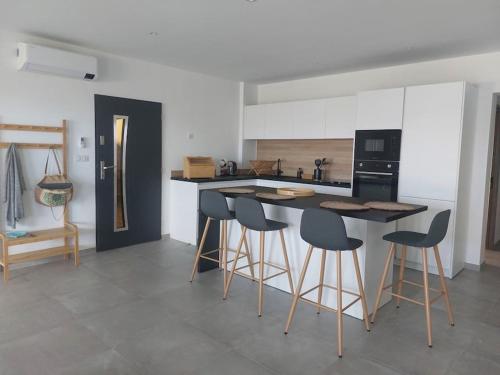 une cuisine avec un îlot et des tabourets de bar dans l'établissement Bella Vita Garancia Grand T3 Neuf avec piscine à Porticcio, à Grosseto-Prugna