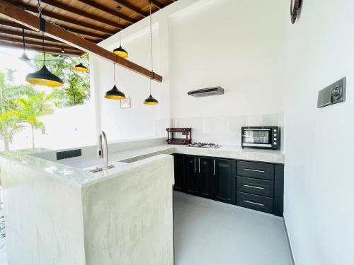 a kitchen with white walls and black cabinets at Thara Inn Villa in Dickwella