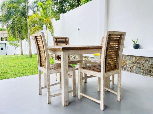 a wooden table and four chairs on a patio at Thara Inn Villa in Dickwella