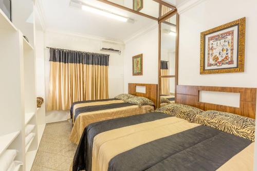 Una habitación de hotel con dos camas y un espejo. en Chalés especiais da Fazenda Itacorá, en Itaipulândia