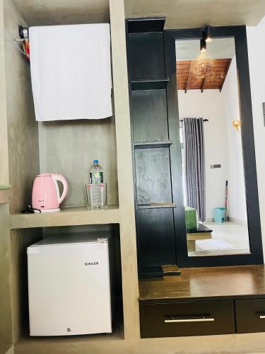 a kitchen with a mirror and a small refrigerator at Thara Inn Villa in Dickwella