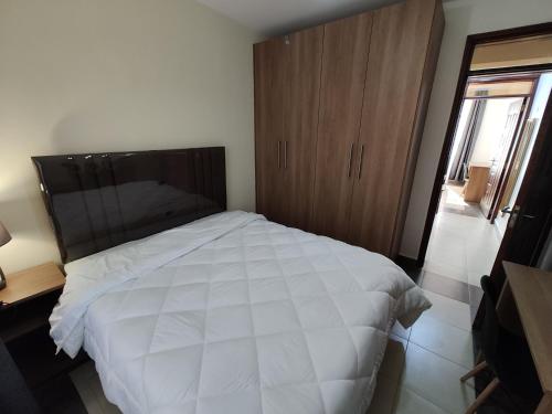 a bedroom with a white bed and a wooden cabinet at The Arches Accola in Nairobi