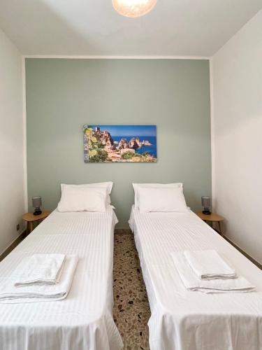 due letti in una stanza con lenzuola bianche di ViLoKa Sicilian Guest House a Calatafimi