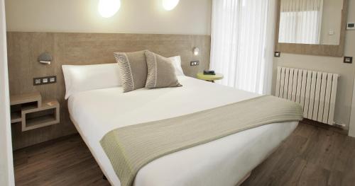 Un dormitorio con una gran cama blanca en una habitación. en Hotel Dos Rios Origen, en Aínsa