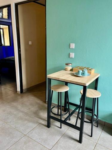 a table with two stools next to a blue wall at La villa d'Isalya in Sainte-Suzanne