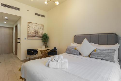 a bedroom with a large white bed with towels on it at Royalton - Serene Studio Apt in the Heart of Meydan District in Dubai