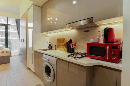 a kitchen with a washing machine and a red microwave at Royalton - Serene Studio Apt in the Heart of Meydan District in Dubai