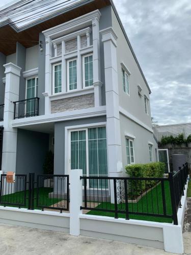 a white house with a black fence at Thai Family Home in Ban Khlong Thewa