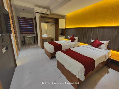 a hotel room with two beds with red pillows at Hotel La Premier in Hyderabad