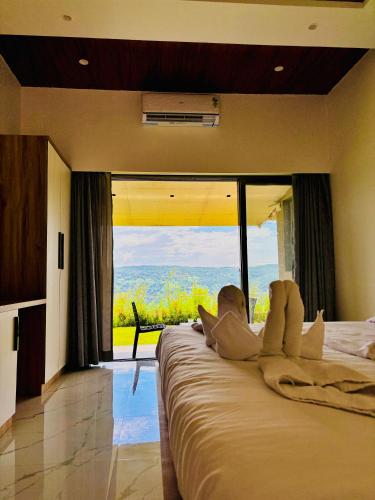 a bedroom with a large bed with a large window at The Breeze Valley in Mahabaleshwar