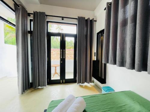 a bedroom with a bed and a large window at Thara Inn Villa in Dickwella