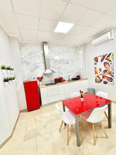 a kitchen with a red table and white chairs at Apartamentos Bobal Requena in Requena