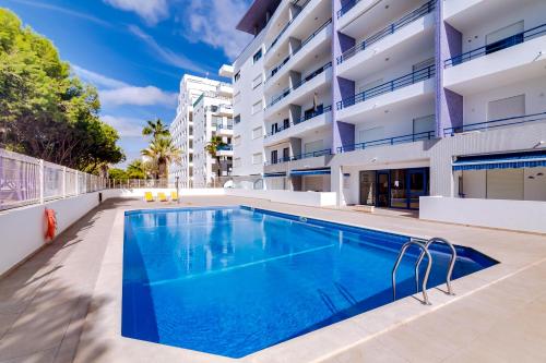 a swimming pool in front of a building at Apartamento Gaivota frente-mar in Quarteira