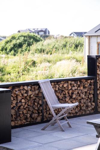 a chair sitting on a patio next to a pile of fire wood at Kallehavegaard Badehotel in Løkken
