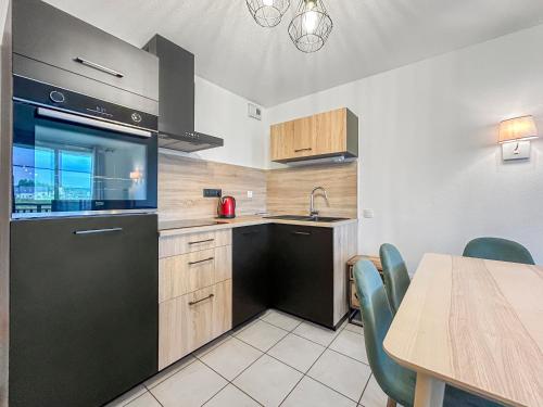 Il comprend une cuisine équipée d'une table et d'un réfrigérateur noir. dans l'établissement Chez Marianne Résidence Piscine Sauna, à Levernois