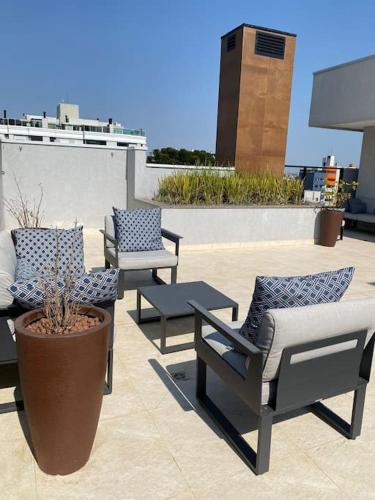 a patio with three chairs and a potted plant at Apartamento Espaçoso in Curitiba