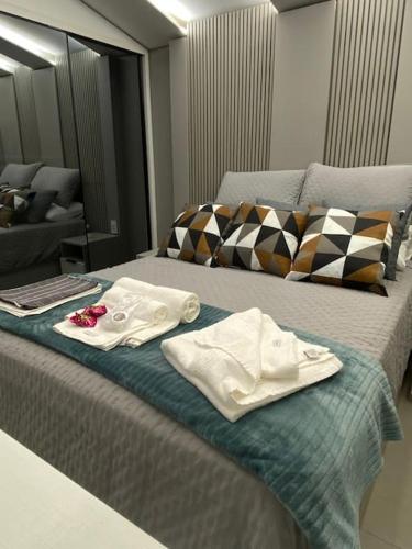 a bed with two white towels on top of it at Apartamento Espaçoso in Curitiba