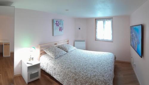 une chambre blanche avec un lit et une fenêtre dans l'établissement Studio indépendant avec jardin, à Saint-Cyr-sur-Loire