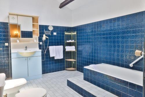 a blue tiled bathroom with a tub and a sink at Hotel Restaurant des Thermes in Castéra-Verduzan