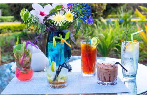 a group of four vases with colorful drinks on a table at Kongoni House in Nairobi