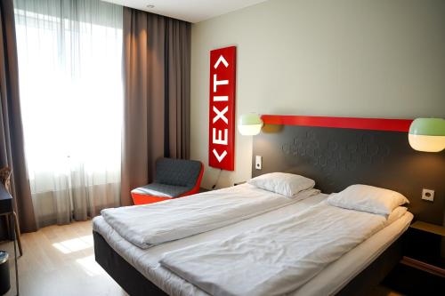 a bedroom with a large bed and a chair at Comfort Hotel Norrköping in Norrköping