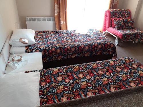 a room with three beds and a chair and a bedspread at My Batumi Apartments in Batumi