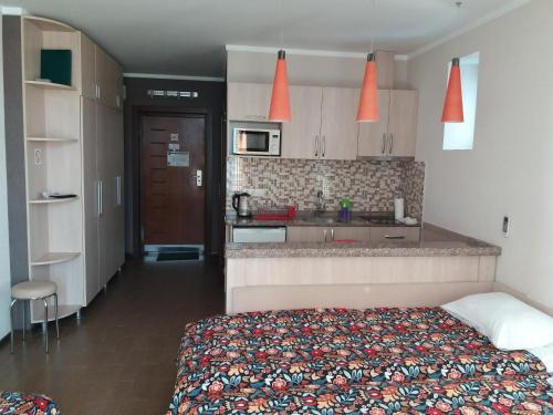 a bedroom with a bed and a kitchen with orange lights at My Batumi Apartments in Batumi