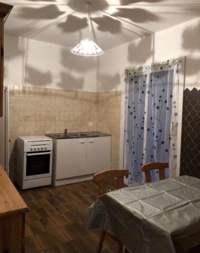 une cuisine avec une cuisinière et une table avec des chaises dans l'établissement Location Estivale en Haute Corse, à Scata