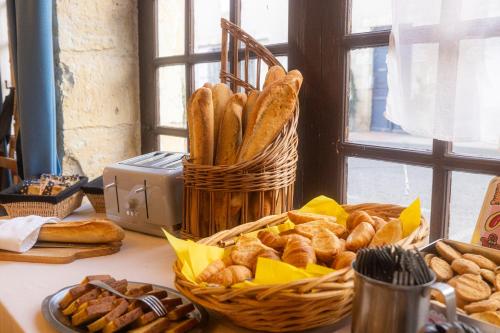Una mesa con una cesta de pan y una cesta de pasteles. en Hotel Restaurant des Thermes, en Castéra-Verduzan