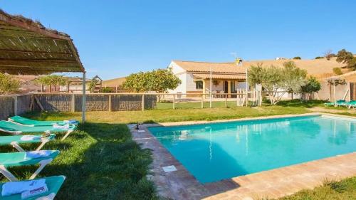 a swimming pool with lounge chairs and a house at Luxurious Villa in Prado del Rey with Pool in Prado del Rey