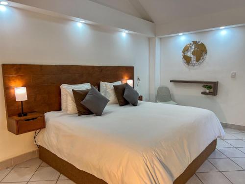a bedroom with a large white bed with a wooden headboard at VILLAS EL ENCANTO in Jalpan