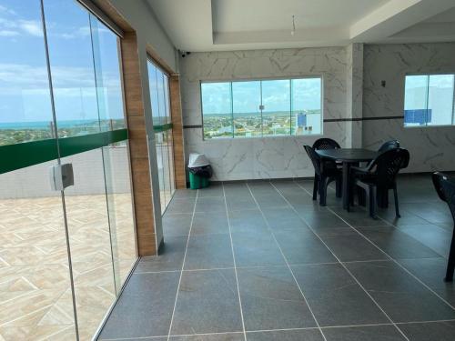 a room with a table and chairs and windows at Flat Litoral Sul da Paraíba- Praia Carabibus in Conde