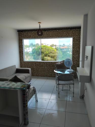 a living room with a couch and a table and a window at Flat Litoral Sul da Paraíba- Praia Carabibus in Conde
