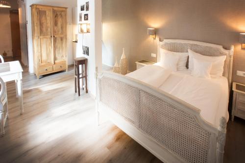 a bedroom with a large white bed and a desk at Hotel Hüttenmühle Hillscheid in Hillscheid