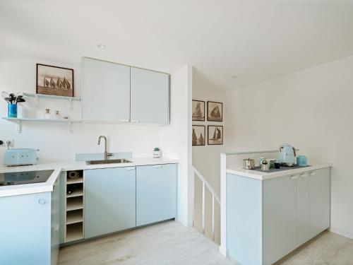 une cuisine blanche avec des armoires blanches et un évier dans l'établissement Holiday Home Les Ormeaux by Interhome, à Saint-Briac-sur-Mer