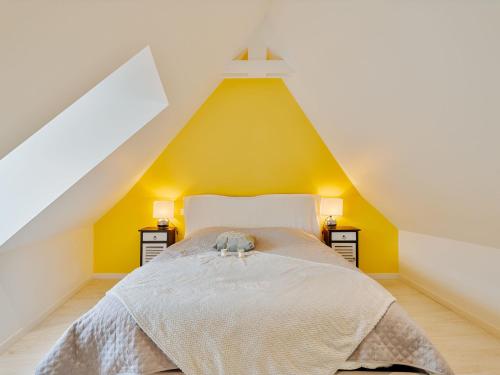une chambre avec un lit avec un mur jaune dans l'établissement Holiday Home Les Ormeaux by Interhome, à Saint-Briac-sur-Mer