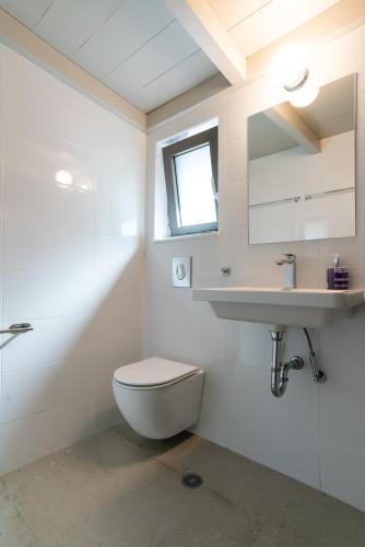 a white bathroom with a toilet and a sink at LEONIDIONHOUSES - The Lykoskufi Villas in Tiros