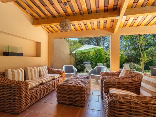 une terrasse avec des chaises et des tables en osier et un parasol dans l'établissement Villa Les Mimosas by Interhome, à Gassin