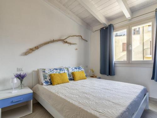 a bedroom with a bed with blue curtains and a window at Apartment Attico Vista Isola by Interhome in Trinità dʼAgultu