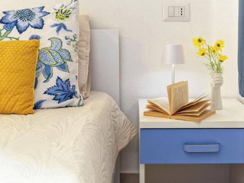 a bed with a yellow pillow and a book on a nightstand at Apartment Attico Vista Isola by Interhome in Trinità dʼAgultu
