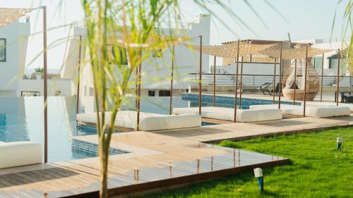 a pool with white lounge chairs and umbrellas next to a building at Mykonos Homes - Stilvolles Apartment mit eigenem Jaccuzzi in Bahçeli